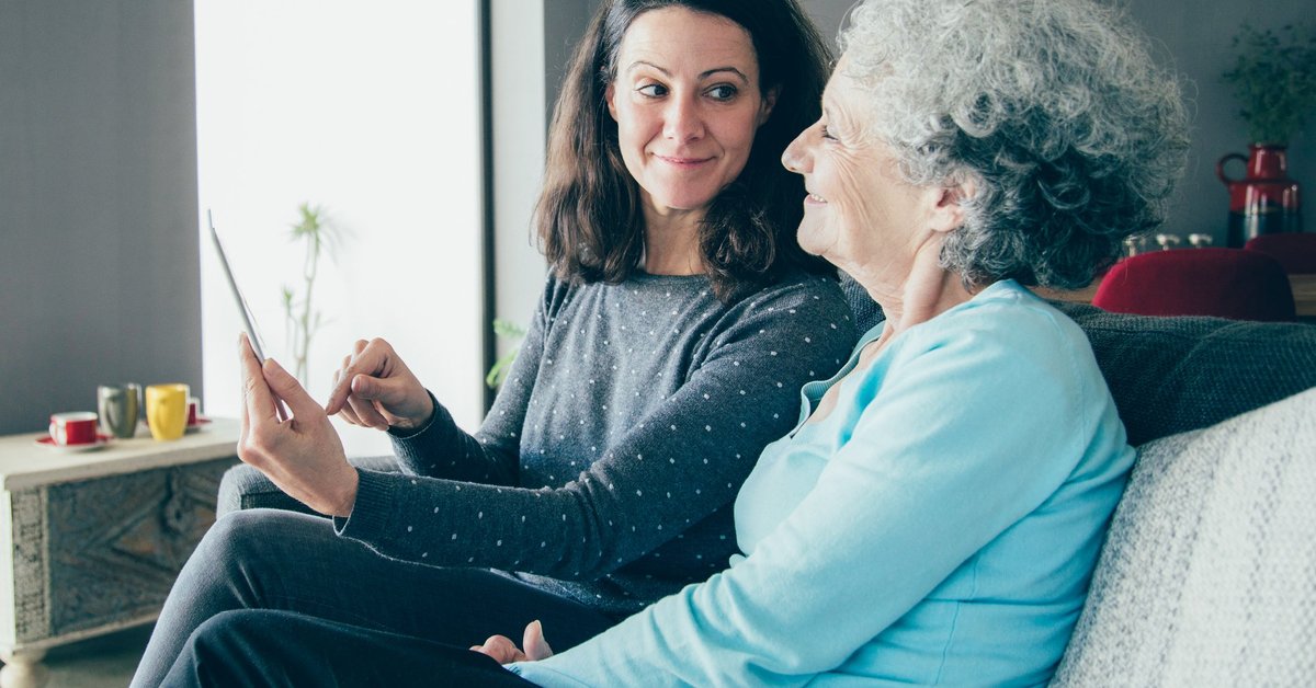 Middle-aged woman showing document to an older woman, possibly her mother.