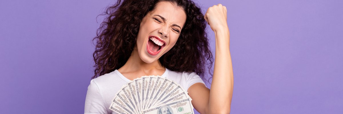 Woman holding a fan of cash and celebrating.