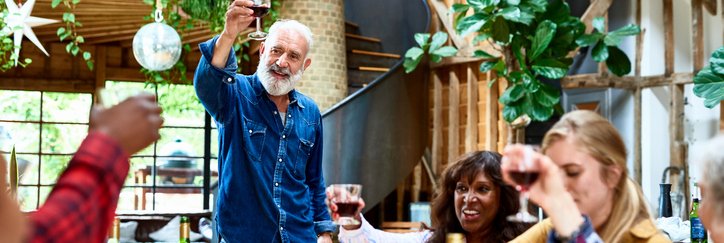 Multi-generational group of people make a toast at the dinner table.