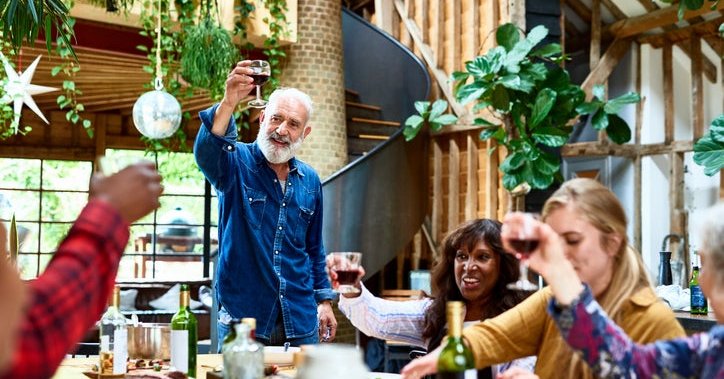Multi-generational group of people make a toast at the dinner table.