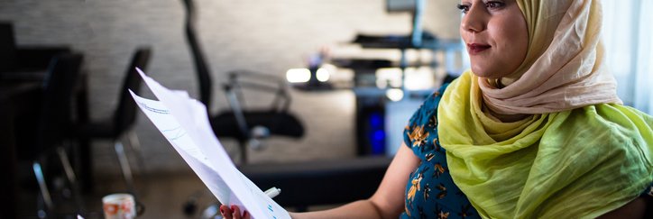 Hijabi looks at investment documents in an office.