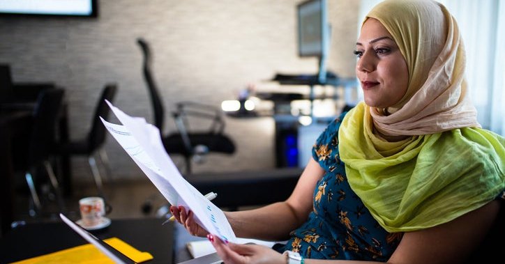 Hijabi looks at investment documents in an office.