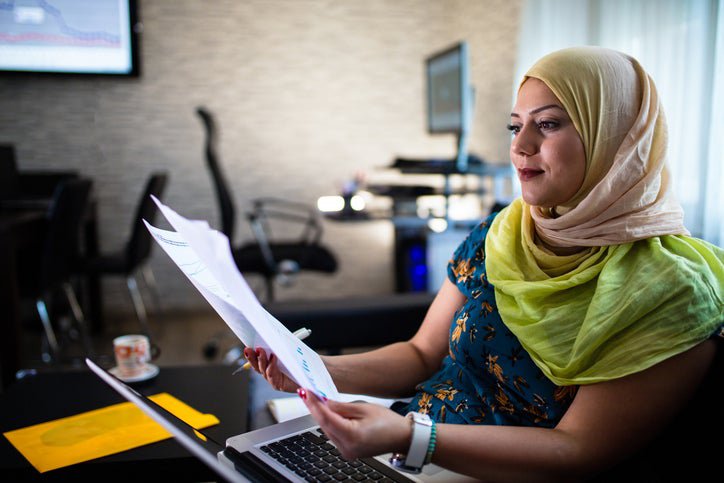 Hijabi looks at investment documents in an office.