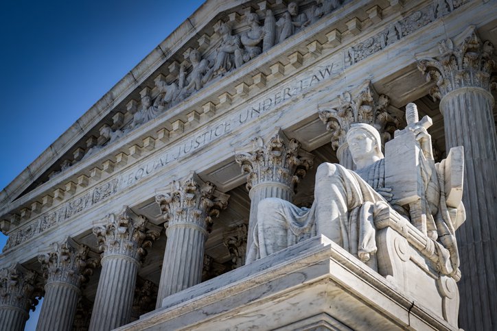 Stone exterior of Supreme Court with Authority of Law statue in foreground.