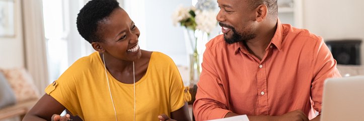 Smiling couple sit at table with paperwork.