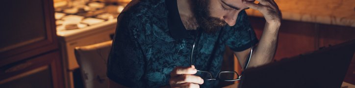 Frustrated man at desk with head in his hands.