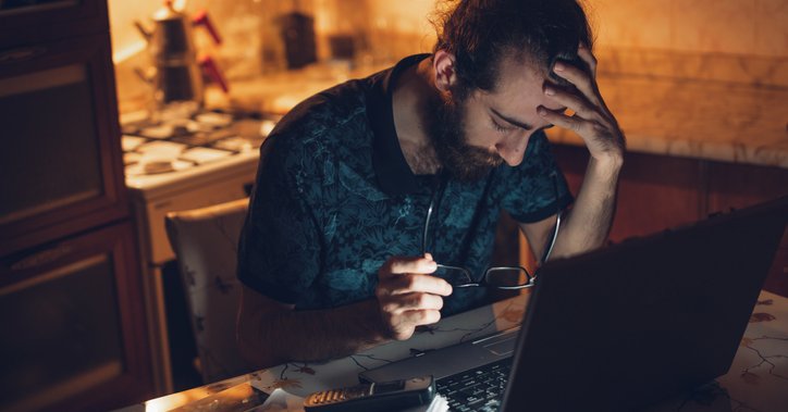 Frustrated man at desk with head in his hands.