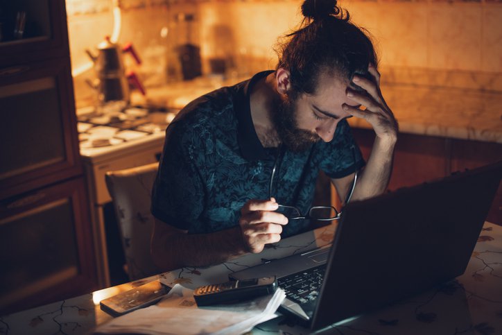 Frustrated man at desk with head in hands.