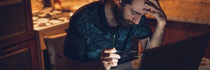 Frustrated man at desk with head in his hands.