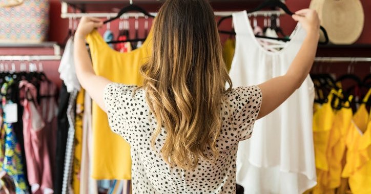 Woman shopping at a clothing store chooses between two shirts