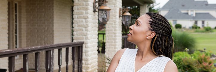 Woman stands outside house with a clipboard