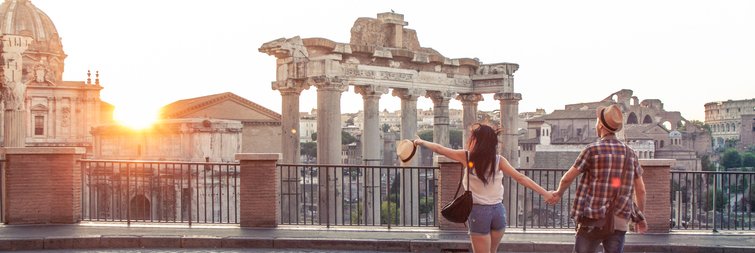 Young couple walk towards the Roman Forum in Rome as sun sets.