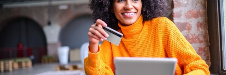 African American woman happily uses her credit card to make an online purchase.