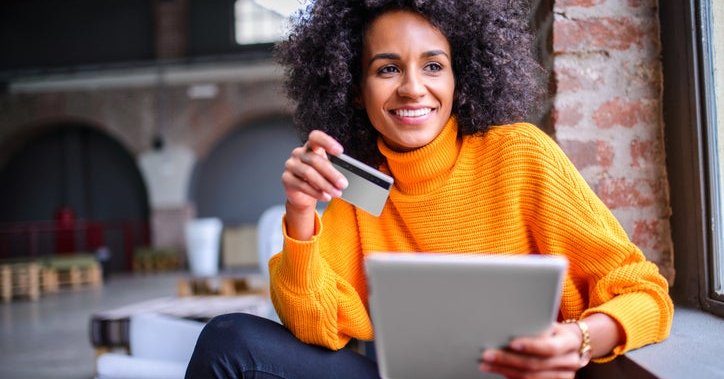 African American woman happily uses her credit card to make an online purchase.