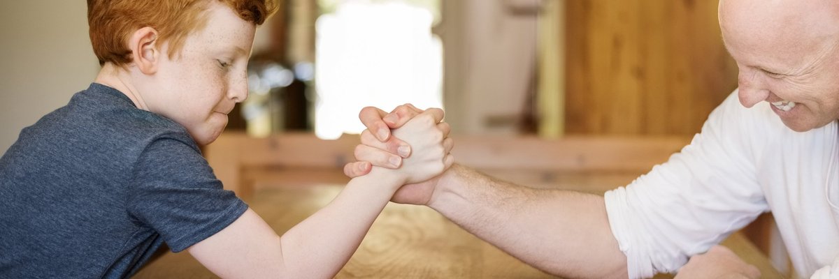 Small child defeating grown man at arm wrestling.