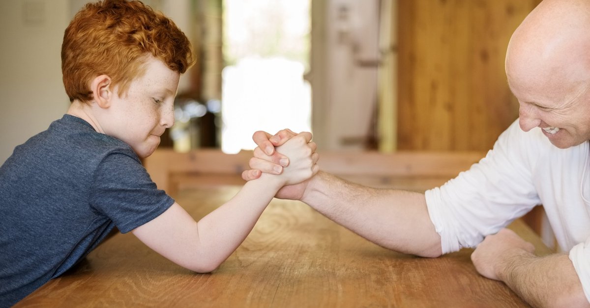 Small child defeating grown man at arm wrestling.