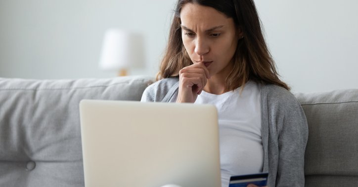 Woman on sofa with credit card in her hand and laptop.