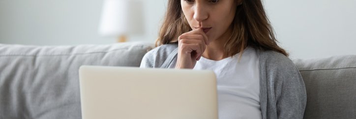Woman on sofa with credit card in her hand and laptop.
