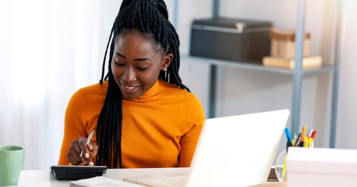 Happy woman makes a calculation at her desk