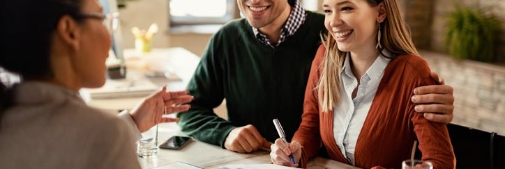 Happy couple in conversation with a business professional at a desk