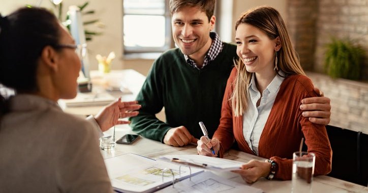 Happy couple in conversation with a business professional at a desk