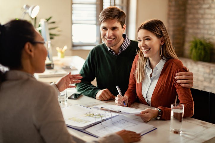 Happy couple in conversation with a business professional at a desk