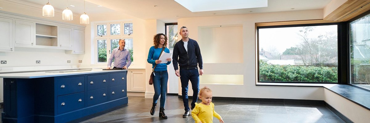 A family tours a large house with a realtor.