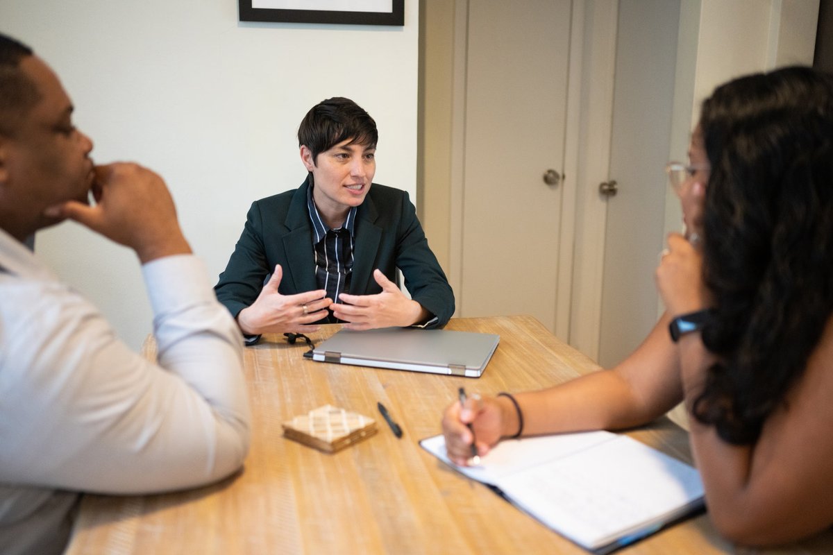 One businessperson leads an office meeting with two other workers.