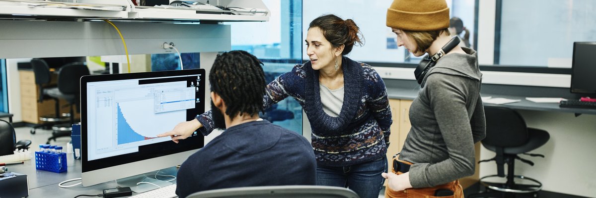 Three office workers discuss a digital graph.