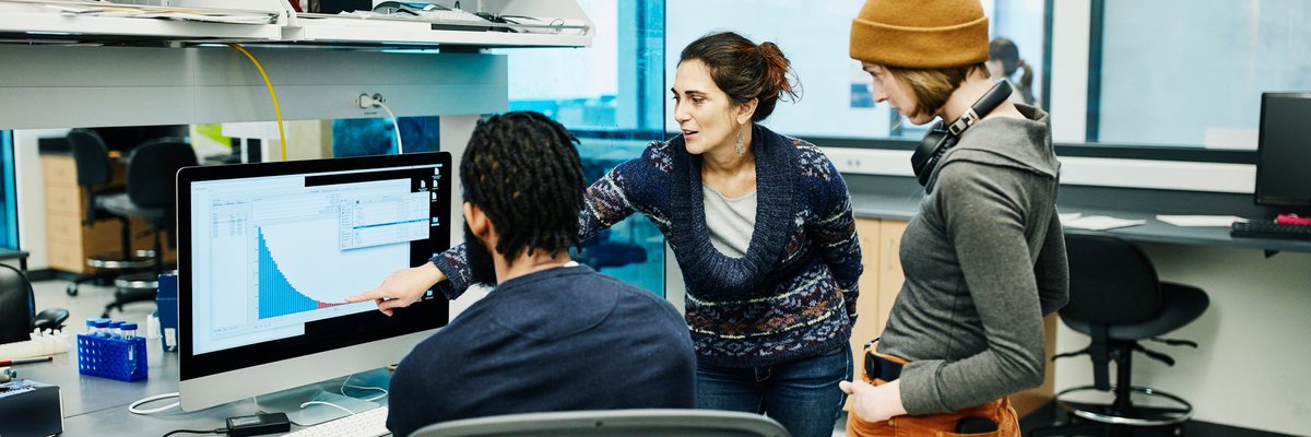 Three office workers discuss a digital graph.