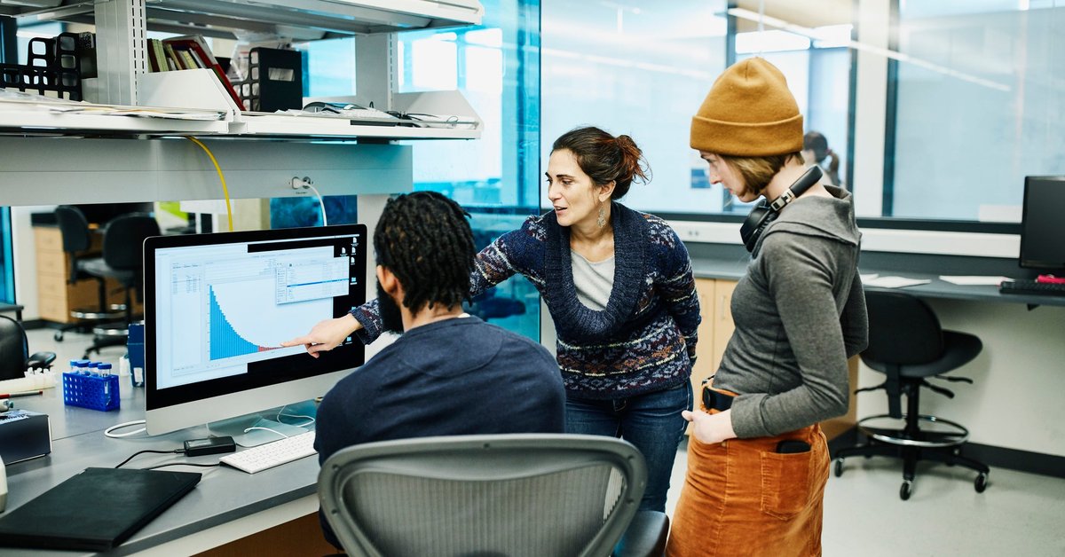 Three office workers discuss a digital graph.