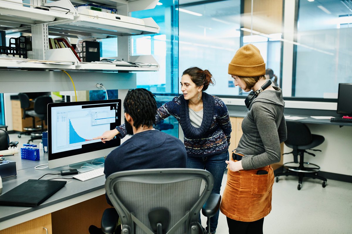 Three office workers discuss a digital graph.