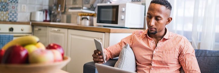 Man reviewing information on his phone and laptop at home