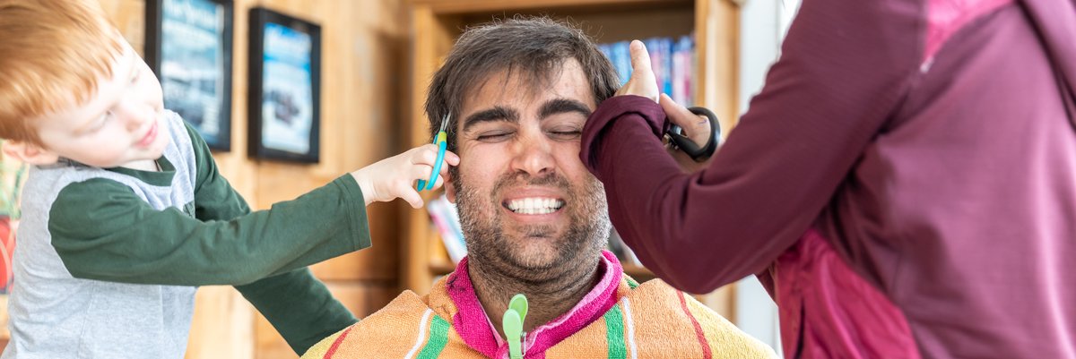 Man getting his hair trimmed at home by children.