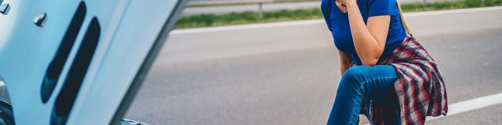 Woman uses her cell phone to call for help after her car broke down.