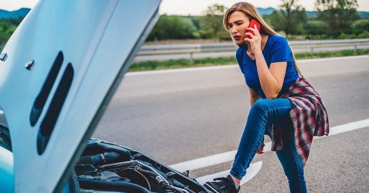 Woman uses her cell phone to call for help after her car broke down.