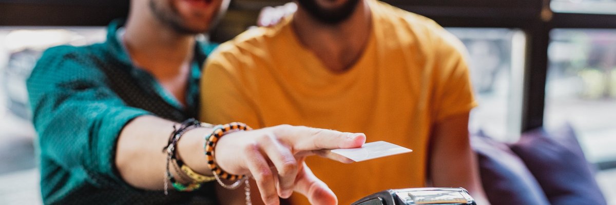 A couple smiles as they use a contactless credit card reader in a restaurant.