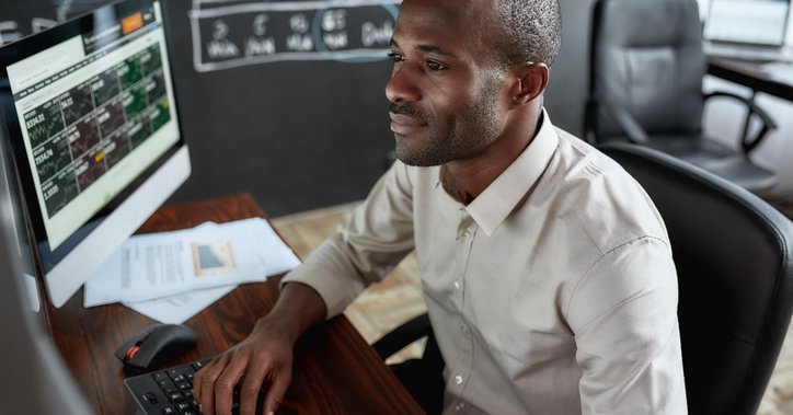 Man sitting in front of several screens trading stocks.