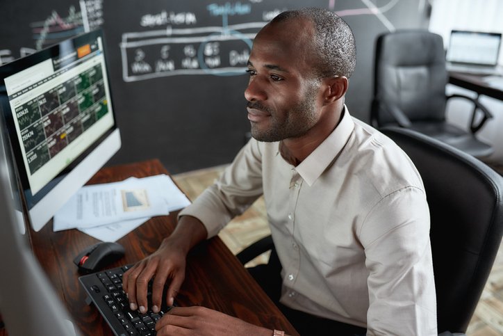 Man sitting in front of several screens trading stocks.