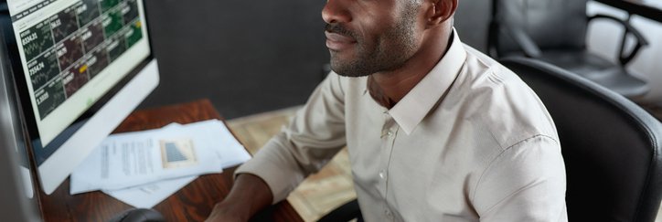 Man sitting in front of several screens trading stocks.