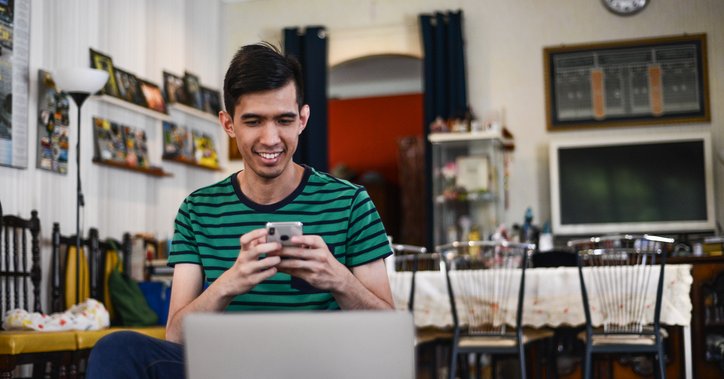 Happy man checks his phone and laptop at home