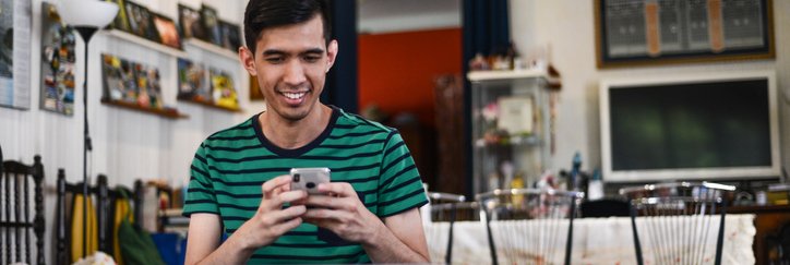 Happy man checks his phone and laptop at home