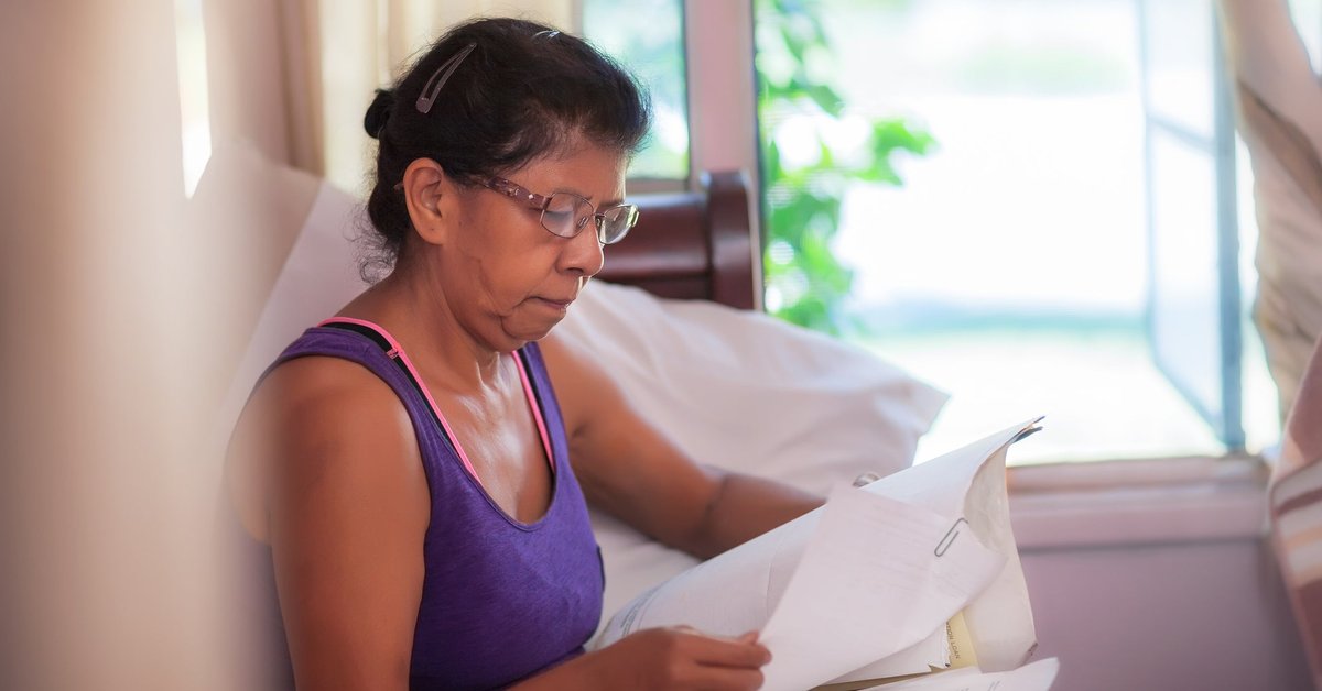 A homeowner compares print-outs of monthly mortgage statements on the couch.