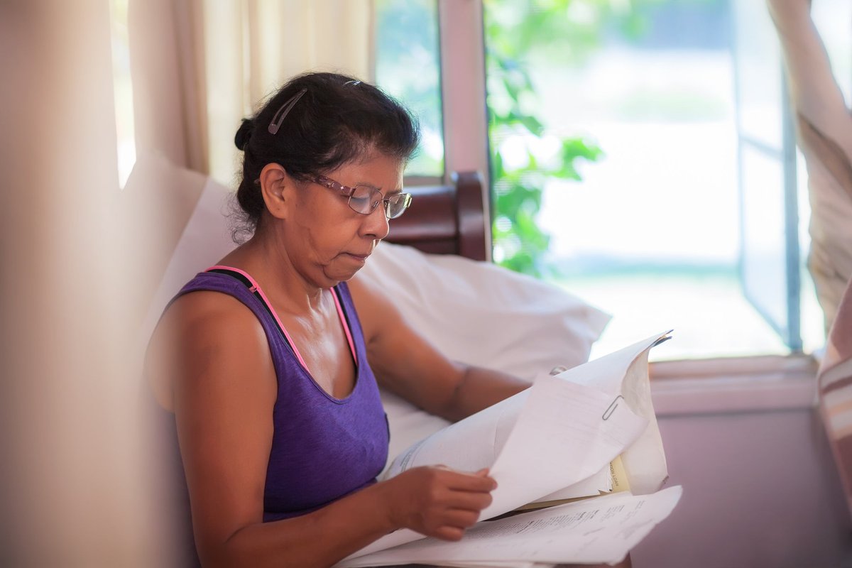 A homeowner compares print-outs of monthly mortgage statements on the couch.