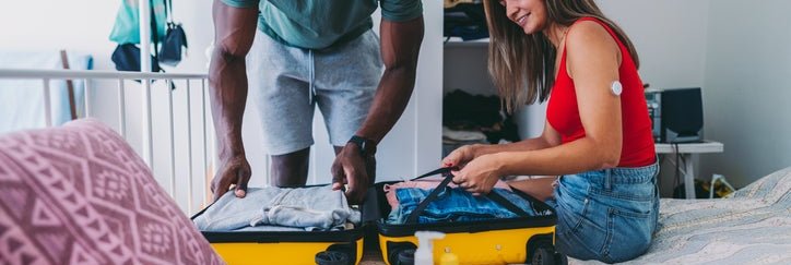 A couple packs a suitcase for traveling, including a wallet and passport.