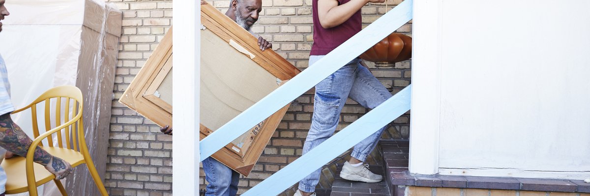 A family carries various furniture into their new house.