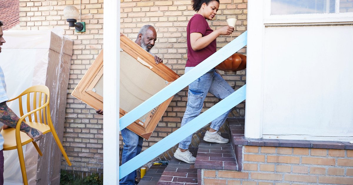 A family carries various furniture into their new house.