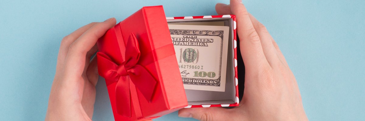 Person opening small gift box with cash inside.