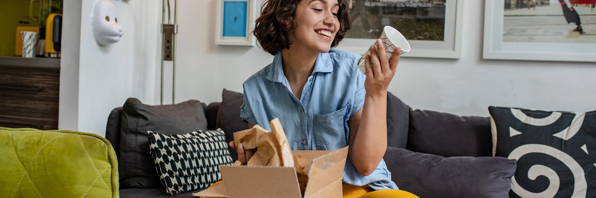 A young adult unpacks a delivered package on the couch.