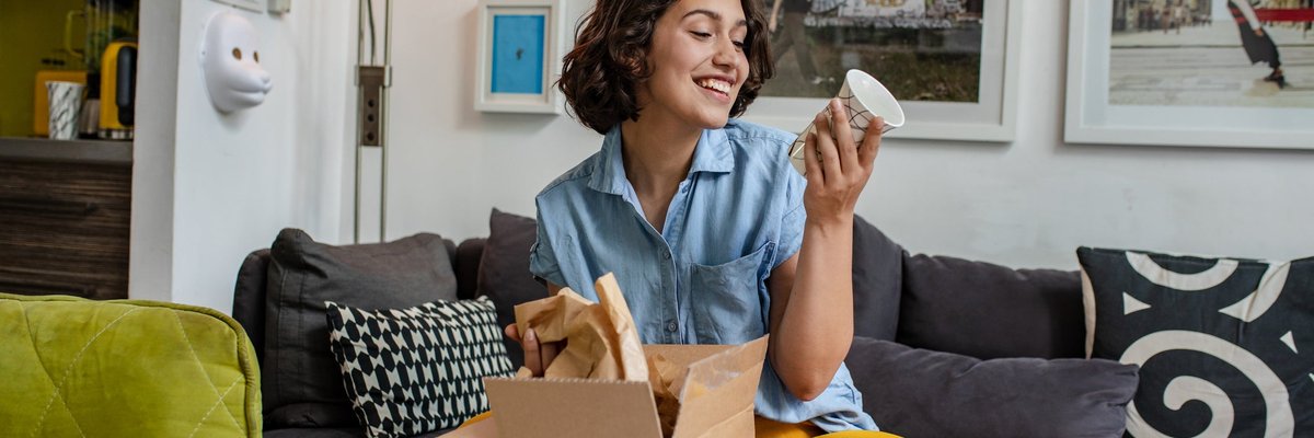 A young adult unpacks a delivered package on the couch.